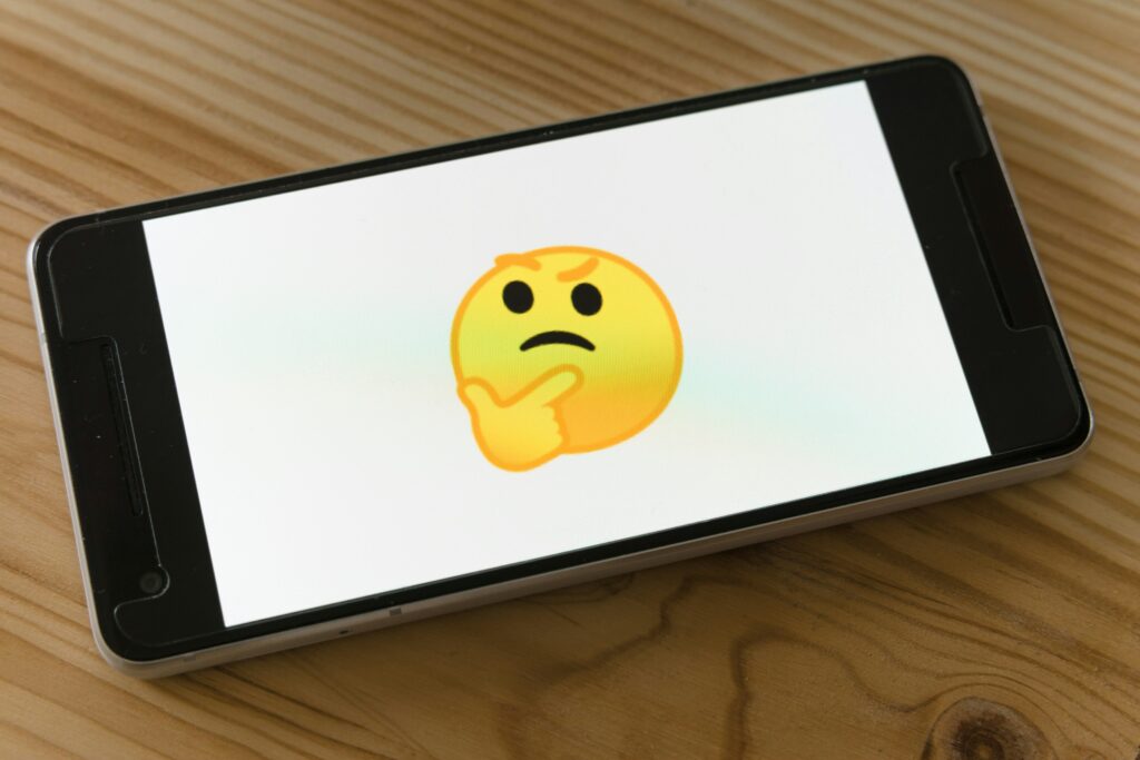 Emoji pensativo exibido na tela de um smartphone.